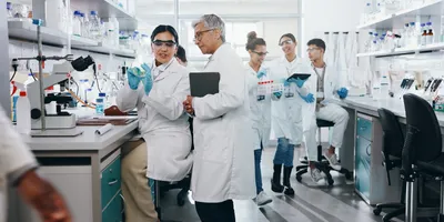 Group of scientists talking and working together in a modern lab environment, emphasizing laboratory leadership
