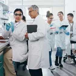 Group of scientists talking and working together in a modern lab environment, emphasizing laboratory leadership