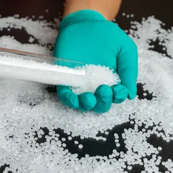 Plastic beads on green gloved hand.