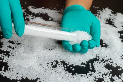 Plastic beads on green gloved hand.