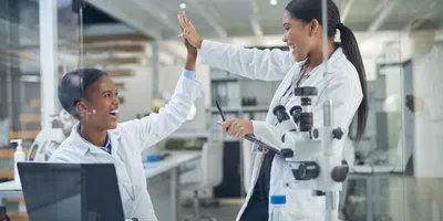 Female scientists high-fiving as a form of encouragement in labs
