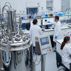 A photo showing two scientists monitoring a precision fermentation bioreactor in a laboratory.
