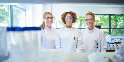 Three women scientists wearing lab coats and PPE, signifying the importance of career development for women in science