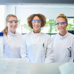 Three women scientists wearing lab coats and PPE, signifying the importance of career development for women in science