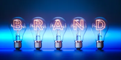 Five lightbulbs with glowing filaments spelling out the word "BRAND," representing the concept of lab branding and its impact on reputation and identity.