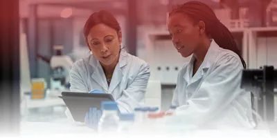 Two women scientists view a tablet
