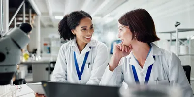 Two lab staff smiling and engaging in conversation