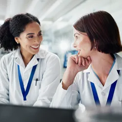 Two lab staff smiling and engaging in conversation
