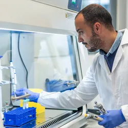 Lab technician using fume hood, optimizing processes to support energy efficiency programs