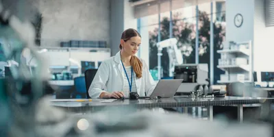A scientist in a lab coat uses a laptop, representing the future of chromatography and the role of AI in streamlining lab management workflows.