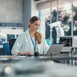 A scientist in a lab coat uses a laptop, representing the future of chromatography and the role of AI in streamlining lab management workflows.