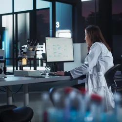 A scientist in a modern laboratory analyzing data on a computer screen, illustrating cloud-based lab informatics and FAIR data practices.