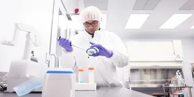 Scientist pipetting in lab, demonstrating proper PPE and biosafety protocols