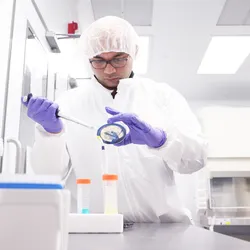 Scientist pipetting in lab, demonstrating proper PPE and biosafety protocols