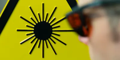 Person wearing laser protective eyewear near warning sign