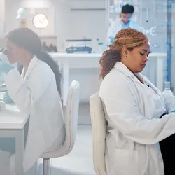 Two scientists in a modern laboratory work at microscopes and computers, illustrating streamlined lab operations and well-coordinated workflows.