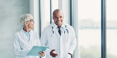  Healthcare provider and diagnostic lab manager talk as they walk through a hallway.