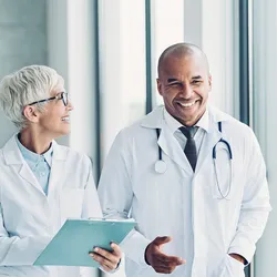  Healthcare provider and diagnostic lab manager talk as they walk through a hallway.