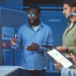 Three colleagues discussing innovative ideas in front of screen in conference room