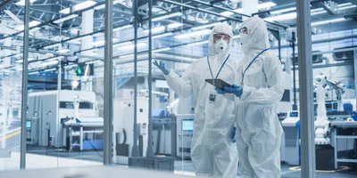 Researchers in cleanroom discussing materials R&D processes.