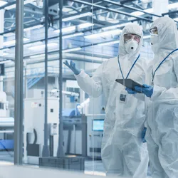 Researchers in cleanroom discussing materials R&D processes.