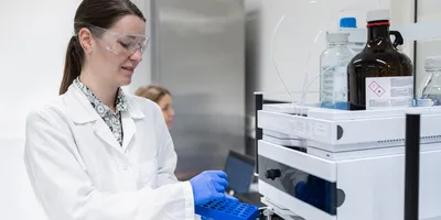 A team of female pharmacists in the production laboratory uses a high-resolution liquid chromatography device or HPLC SYSTEM to analyze and prepare a new product.