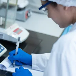 Lab technician weighing liquid for World Quality Week 2025 preparation.