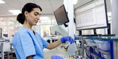 Laboratory technician working on patient samples in a clinical lab setting.
