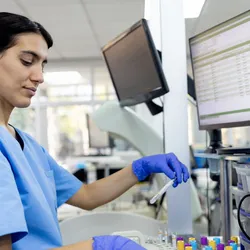 Laboratory technician working on patient samples in a clinical lab setting.