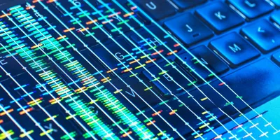 Colorful DNA sequencing data overlaid on a computer keyboard, symbolizing bioinformatics and turning biological data into actionable insights