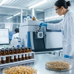 Scientist performing pesticide residue testing using LC-MS/MS equipment in a modern agricultural laboratory for food safety compliance.