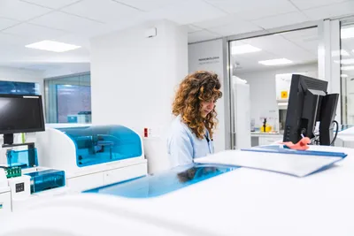 Lab professional reviewing automated syphilis testing workflow results at clinical analyzer workstation