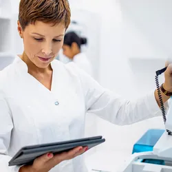 Lab manager reviewing lab equipment usage data on a tablet.