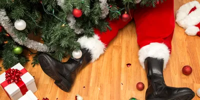 Santa's legs beneath a Christmas tree with gifts, highlighting how holiday movie mishaps relate to lab safety