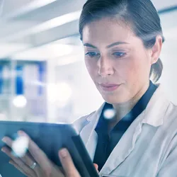Shot of a young woman using a digital tablet in a lab, demonstrating the use of AI in science