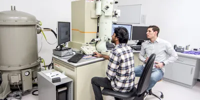 Researchers operate advanced microscopy equipment for nanomaterials analysis.