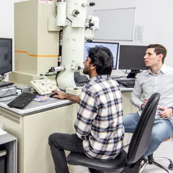 Researchers operate advanced microscopy equipment for nanomaterials analysis.