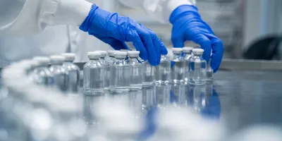 Laboratory hands placing vials on a stainless steel surface, highlighting life sciences manufacturing investment.