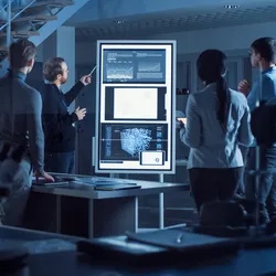 Group of lab professionals looking at screen and discussing strategic planning and SMART goals