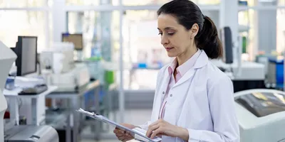 Latin American doctor reading some tests results on a clipboard while working at the laboratory