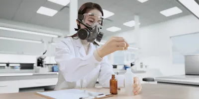 Woman wearing a respirator conducting laboratory tests.