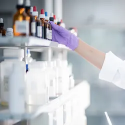 Lab worker organizing chemical bottles under OSHA standards.