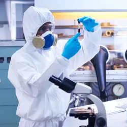 Individual in a lab setting wearing a respirator to handle potential hazardous chemicals