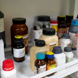 Laboratory shelf with a mix of chemical substances in various bottles.