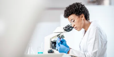 Female scientist marking a test tube next to a microscope
