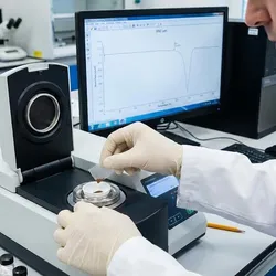Scientist loading a polymer sample into a Differential Scanning Calorimeter (DSC) instrument to analyze thermal stability and transitions in agricultural plastics.