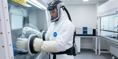 Laboratory technician in full protective equipment (PPE) working in a glovebox to handle nanomaterials safely during particle analysis