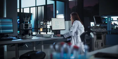 Asian Female Scientist Working on a Desktop Computer, Analyzing DNA Samples Alone in the Evening.