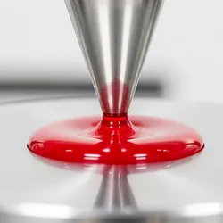 Close-up of a red liquid droplet being tested with a viscometer