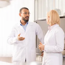 Two colleagues standing in lab having a serious conversation